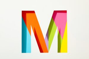 Multicolor letter M on white background, space for text